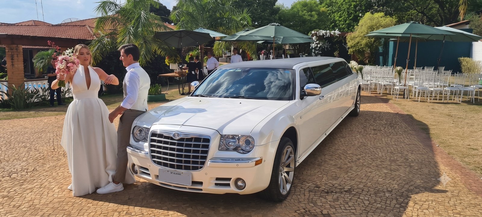 Noivos ao lado da limousine Chrysler 300C branca em festa de casamento ao ar livre em São Paulo