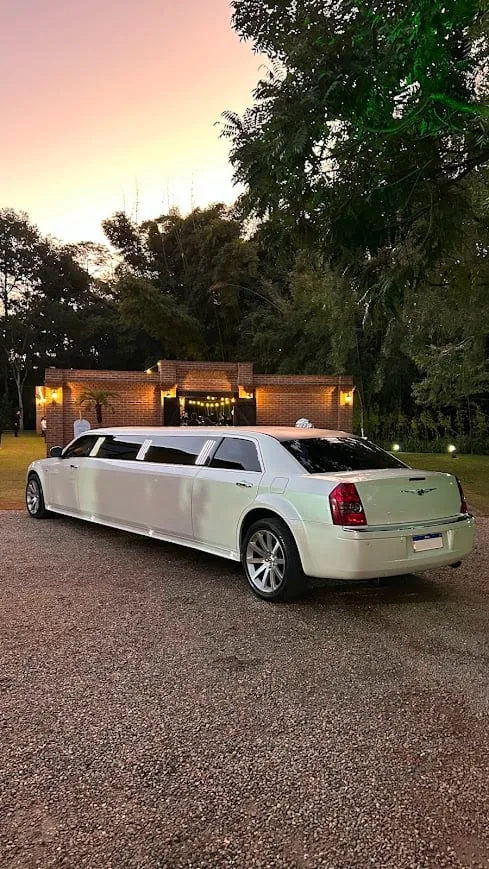 Limousine Chrysler 300C branca vista de traseira em três quartos, ao entardecer, em frente a um espaço de eventos